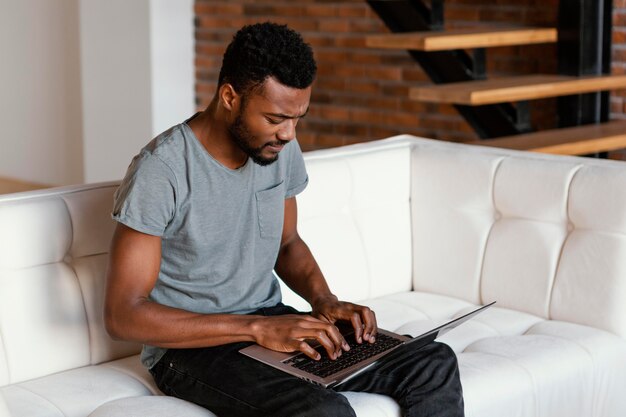 Uomo del colpo medio sul divano digitando