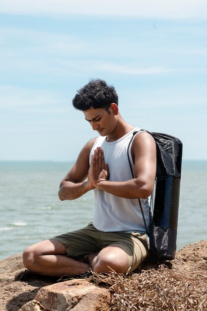 Uomo del colpo pieno che fa yoga in natura