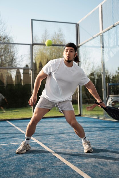 Uomo del colpo pieno che gioca a paddle tennis all'aperto