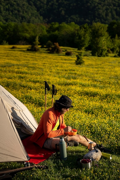 Uomo del colpo pieno che si siede in tenda