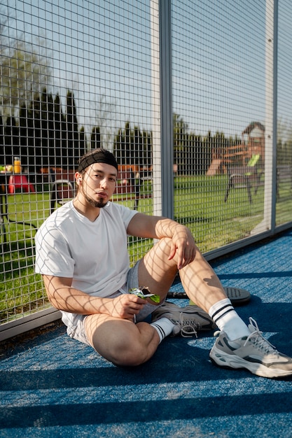 Uomo del colpo pieno che si siede nel campo da paddle tennis