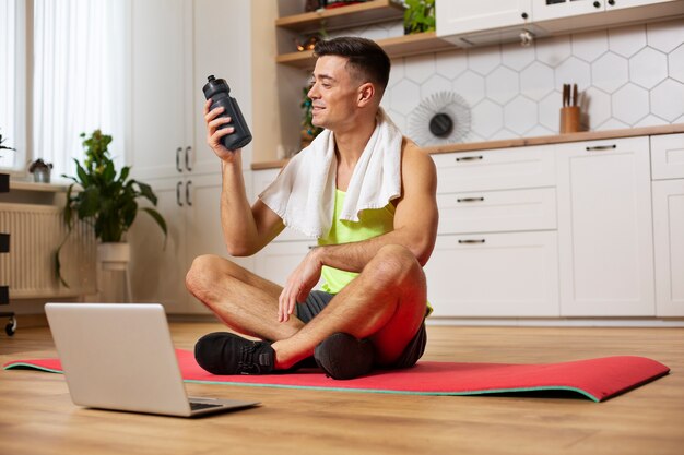 Uomo del colpo pieno che si siede sulla stuoia di yoga