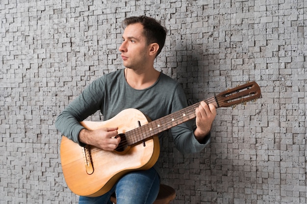 Uomo del musicista in casa a suonare la chitarra classica