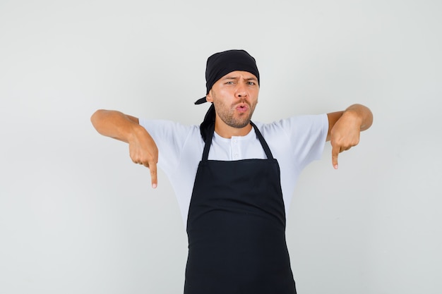 Uomo del panettiere che indica le dita verso il basso in t-shirt