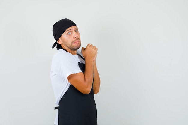 Uomo del panettiere che stringe le mani nel gesto di preghiera in t-shirt