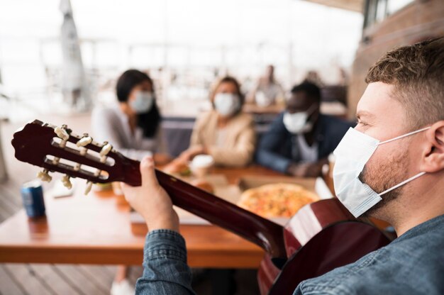 Uomo del primo piano che gioca chitarra al tavolo