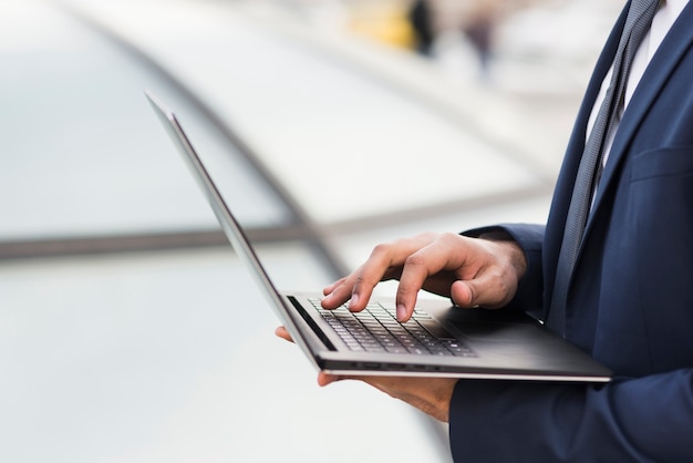 Uomo del primo piano che lavora al computer portatile