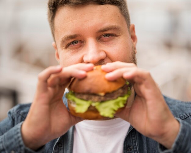Uomo del primo piano che mangia hamburger delizioso