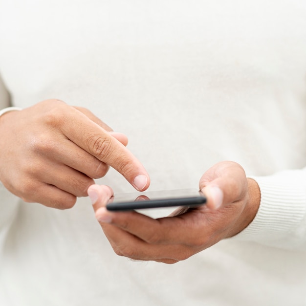 Uomo del primo piano che passa in rassegna il suo telefono cellulare