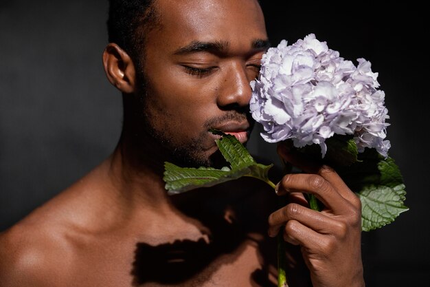 Uomo del primo piano che posa con il bel fiore