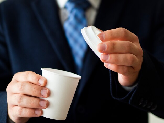 Uomo del primo piano che tiene il piccolo modello della tazza del caffè