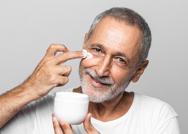 Uomo del primo piano che usando crema per il viso