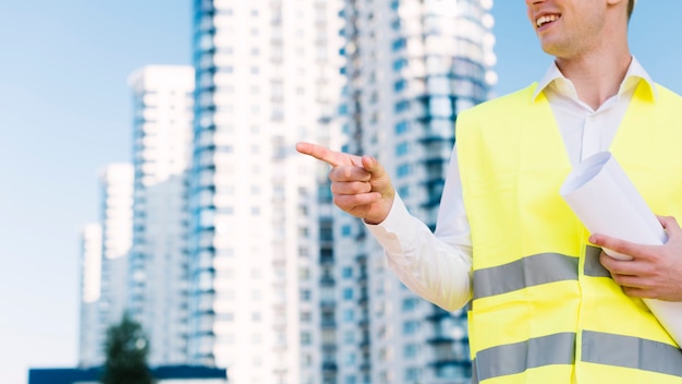 Uomo del primo piano con la maglia di sicurezza che indica a qualcosa