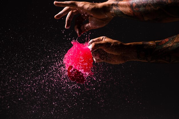 Uomo del primo piano schioccando un pallone con pittura rossa