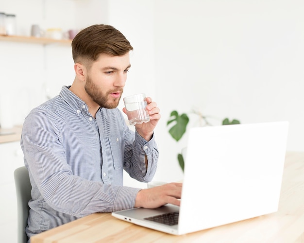 Uomo del ritratto a casa che lavora al computer portatile