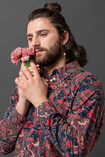 Uomo del ritratto in vestiti alla moda in posa tenendo i fiori