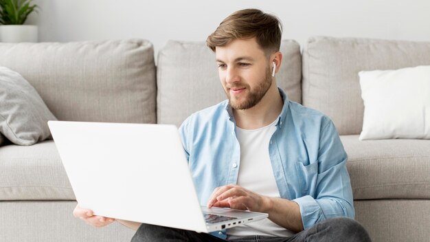 Uomo del ritratto sul pavimento con il computer portatile