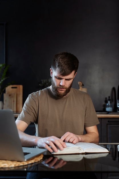 Uomo del tiro medio che legge la Bibbia a casa