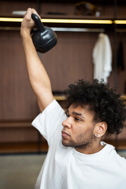 Uomo del tiro medio che tiene il kettlebell in su