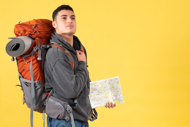 Uomo del viaggiatore di vista frontale con lo zaino che tiene mappa mettendo la mano sul petto