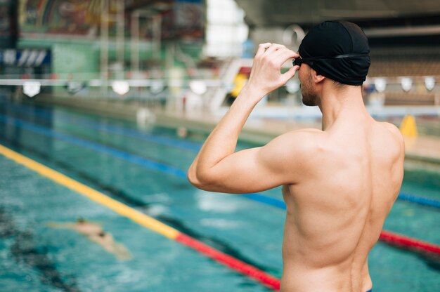 Uomo dell'angolo alto che indossa la cuffia da nuoto