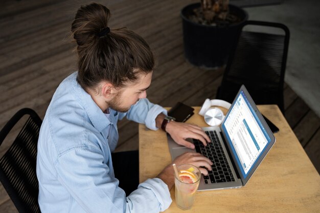 Uomo dell'angolo alto che lavora al computer portatile