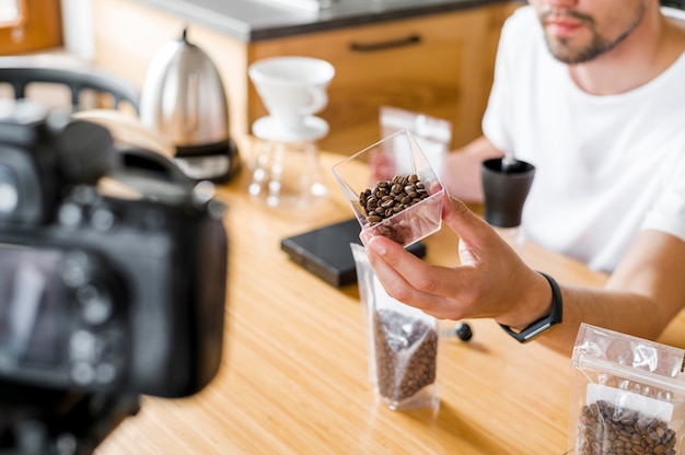 Uomo dell'angolo alto con i chicchi di caffè