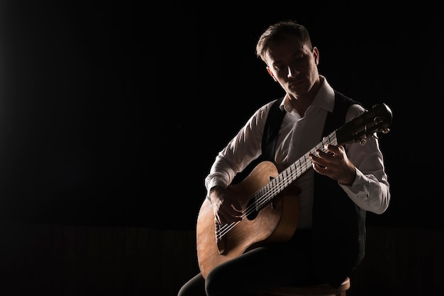 Uomo dell'artista in scena giocando lo spazio classico della copia della chitarra