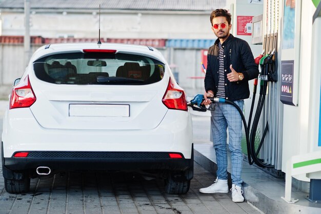 Uomo dell'Asia meridionale o maschio indiano che rifornisce di carburante la sua auto bianca sulla stazione di servizio