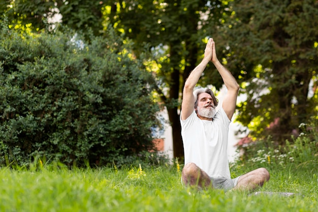 Uomo della foto a figura intera sulla stuoia di yoga all'aperto