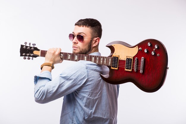 Uomo della rock star con una chitarra isolata sopra la parete bianca