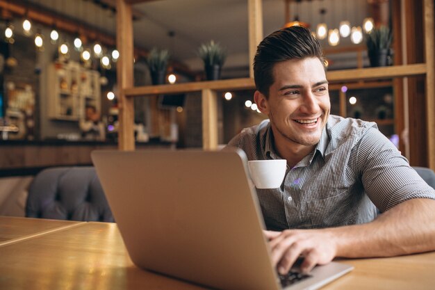 Uomo di affari che lavora al computer portatile in un caffè