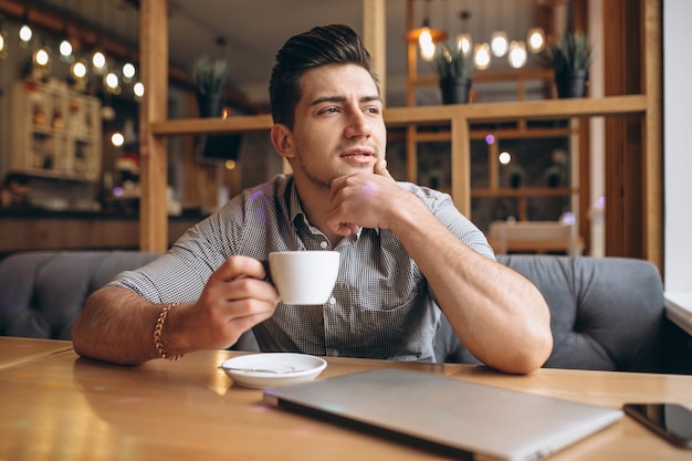 Uomo di affari che lavora al computer portatile in un caffè