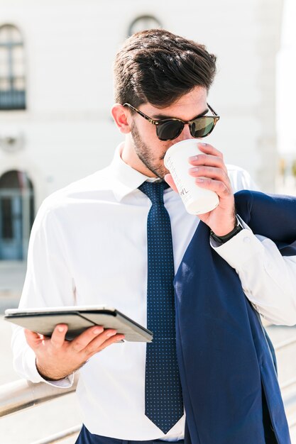 Uomo di affari che per mezzo del suo ridurre in pani e che beve caffè