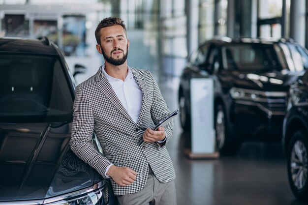 Uomo di affari che sceglie un'auto in uno showroom di auto