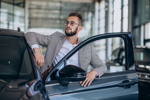 Uomo di affari che sceglie un'auto in uno showroom di auto