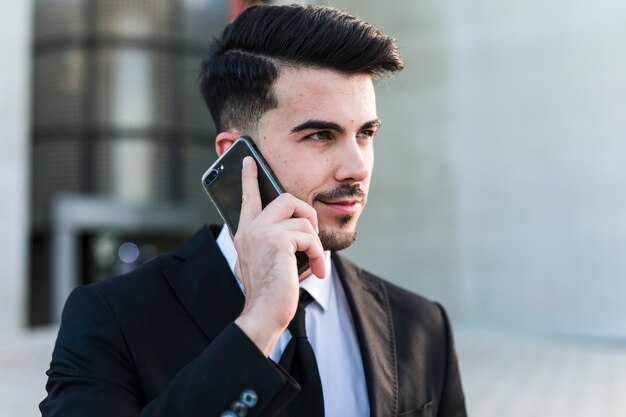 Uomo di affari davanti all&#39;edificio per uffici facendo uso del suo telefono cellulare