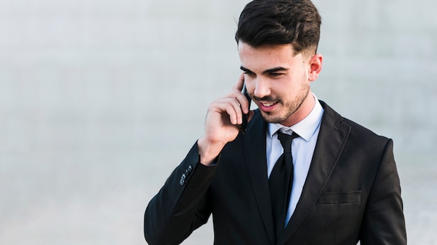 Uomo di affari davanti all&#39;edificio per uffici facendo uso del suo telefono cellulare