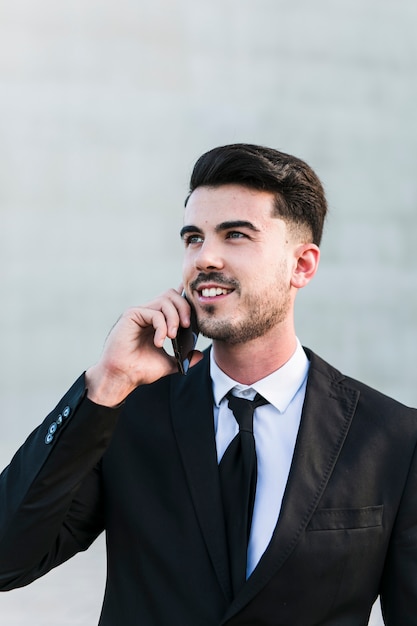 Uomo di affari davanti all&#39;edificio per uffici facendo uso del suo telefono cellulare