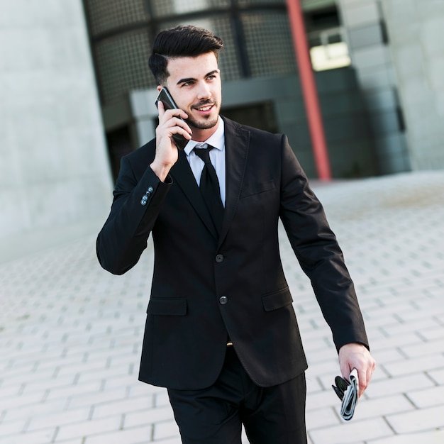 Uomo di affari davanti all&#39;edificio per uffici facendo uso del suo telefono cellulare