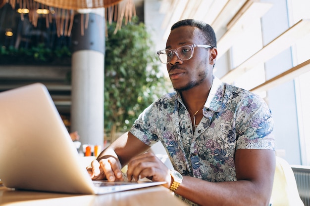 Uomo di affari dell&#39;afroamericano che lavora con il computer portatile in un caffè