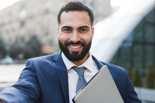 Uomo di affari dell'angolo alto con il computer portatile