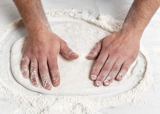 Uomo di alto angolo che impasta la pasta della pizza