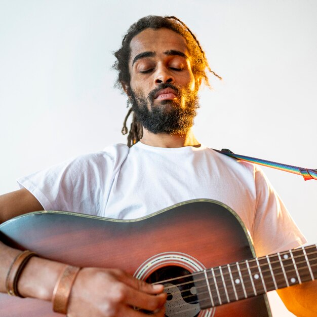 Uomo di angolo basso che gioca la chitarra all'interno