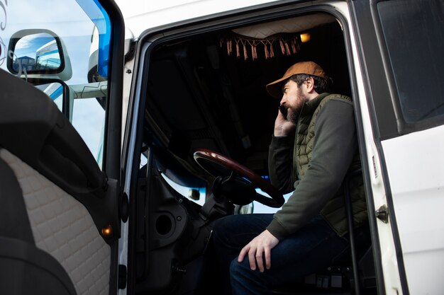 Uomo di angolo basso che parla al telefono in camion