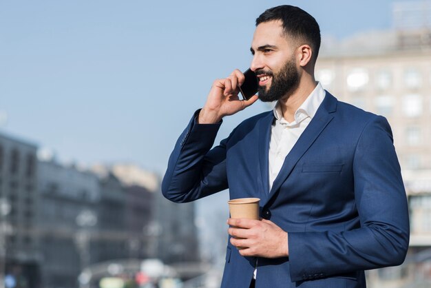 Uomo di angolo basso che parla sopra il telefono