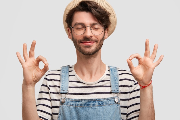 Uomo di Brunet che indossa un cappello e tute di jeans