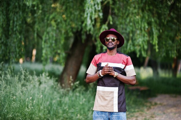 Uomo di colore alla moda ed elegante con cappello e occhiali da sole