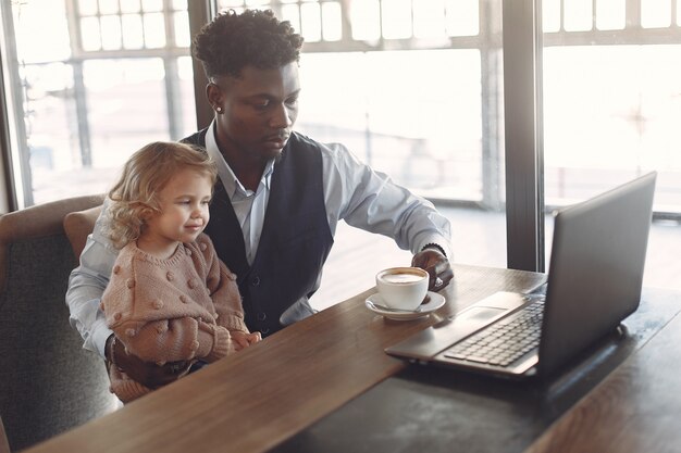 Uomo di colore con la figlia bianca che sta in un caffè