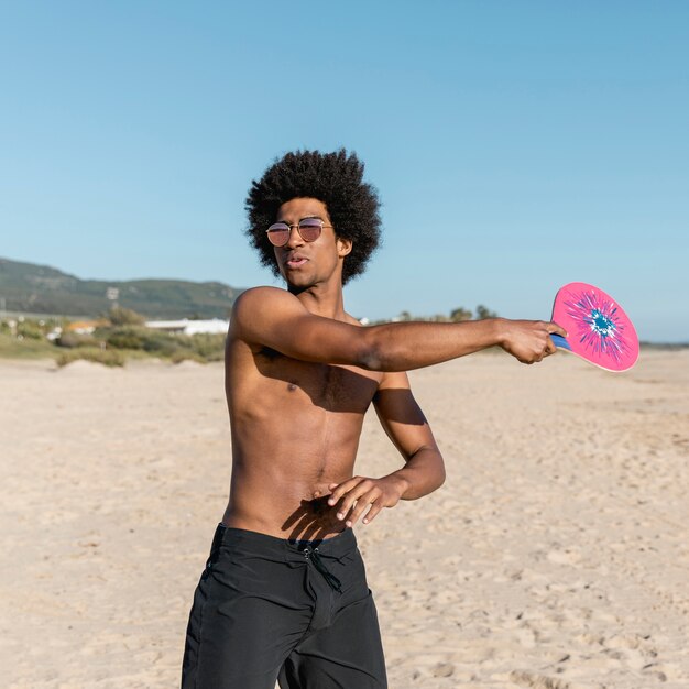 Uomo di colore con racchetta da tennis sulla spiaggia